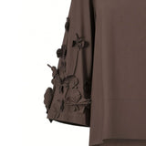 Close-up detail shot of the Meimeij dark brown blouse sleeve highlighting the intricate craftsmanship of the three-dimensional fabric floral elements from BLUE SALON shop.
