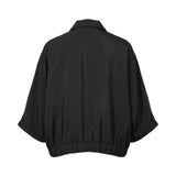 Back view of the Meimeij black blouse showcasing the fluid draped fabric, relaxed shoulders, and the gathered elastic hemline, available at BLUE SALON shop.