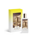 A luxury perfume set featuring the Memo Paris Cap Camarat Eau de Parfum bottle and its presentation box. The rectangular frosted white bottle has a gold cap and a central illustration of a lighthouse shining its light over rocky waves. The box matches the artwork with a vibrant yellow-to-white gradient background, emphasizing the premium "Fleurs Bohèmes" collection branding.