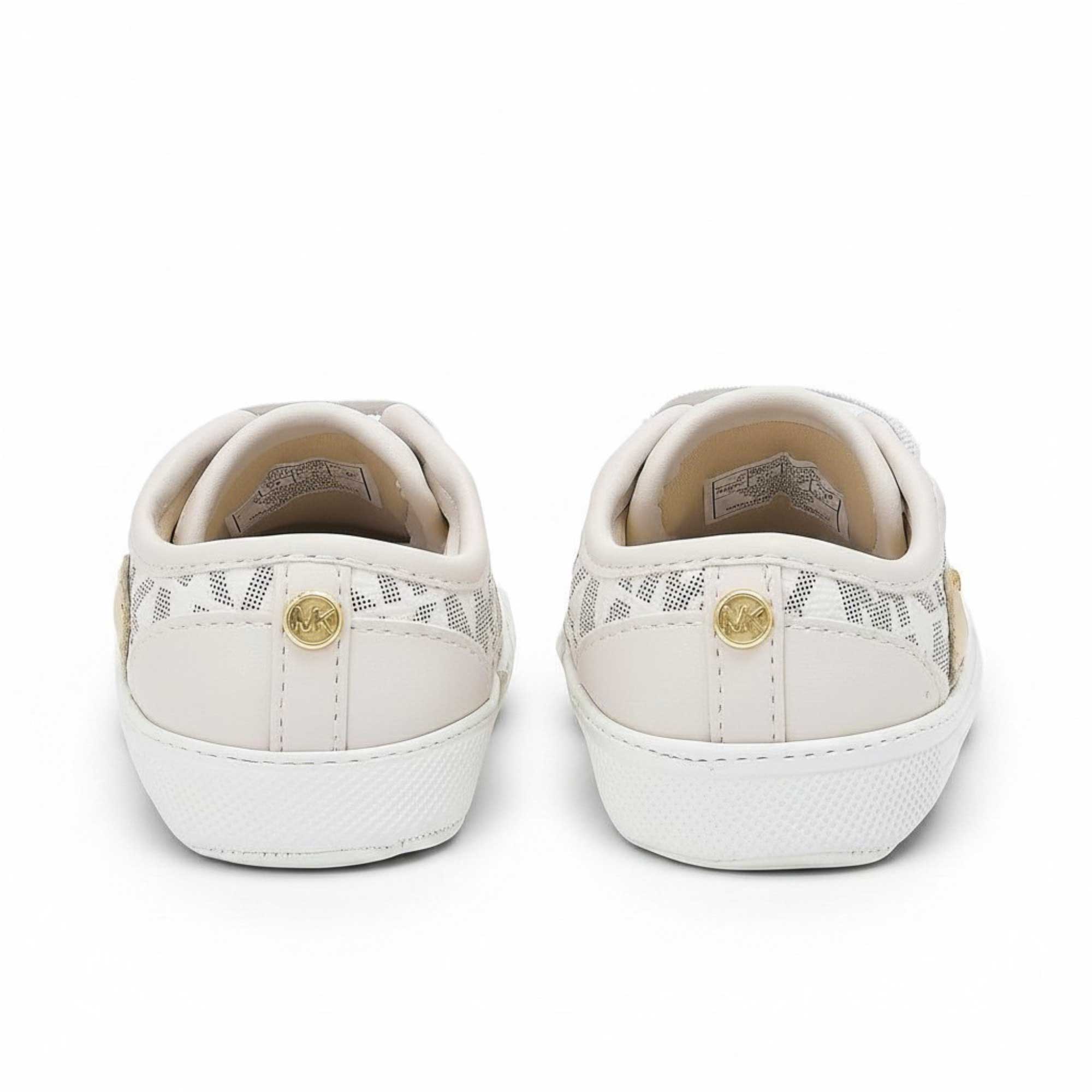 Rear view of the heels of a pair of baby pre-walker shoes, highlighting a cream faux-leather heel strip decorated with a small circular metallic gold MK logo button.
