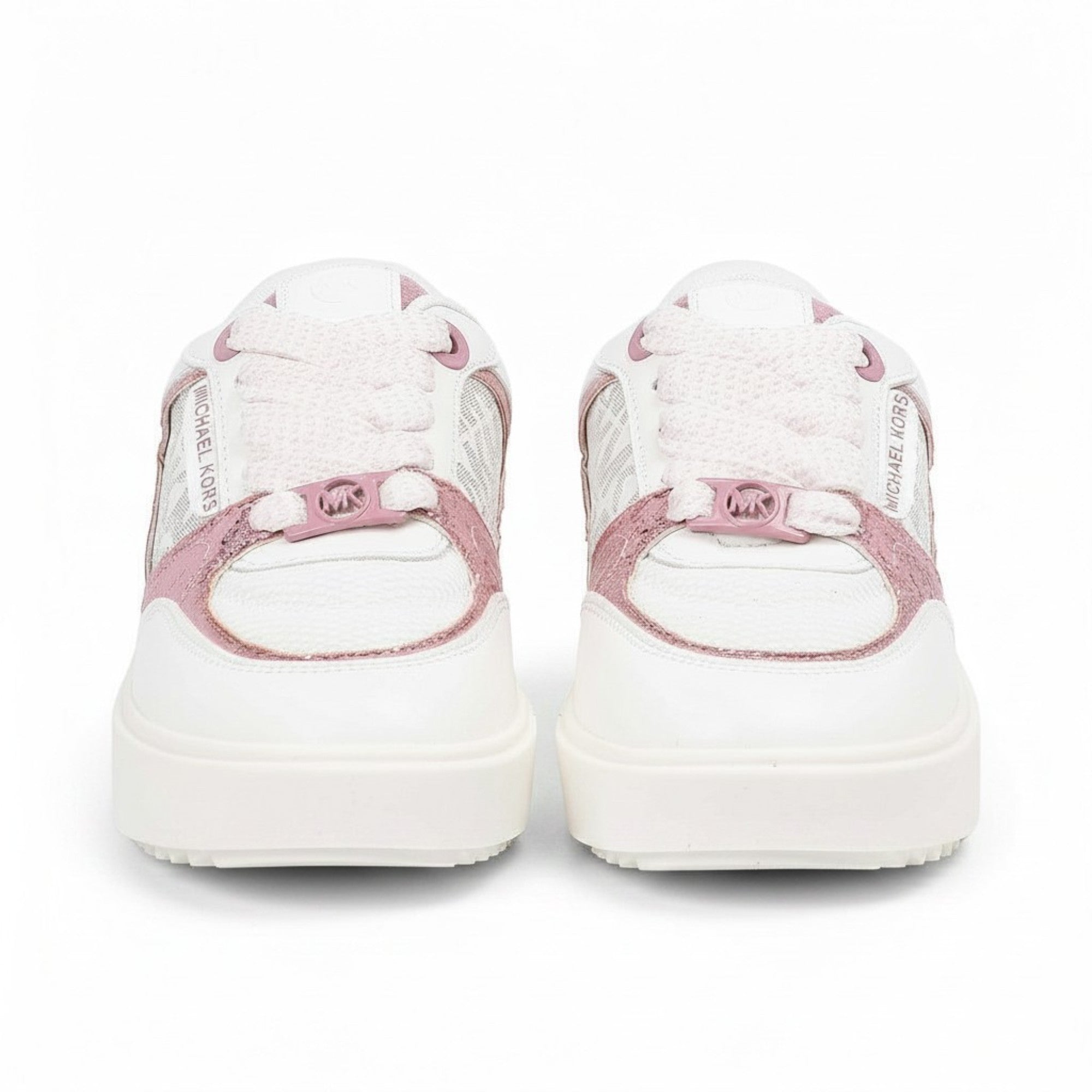 Straight front-facing view of a pair of white Michael Kors sneakers highlighting thick white platform toes, light pink laces, and a metallic pink MK logo hardware piece secured at the base of the laces.