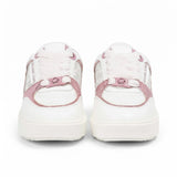 Straight front-facing view of a pair of white Michael Kors sneakers highlighting thick white platform toes, light pink laces, and a metallic pink MK logo hardware piece secured at the base of the laces.