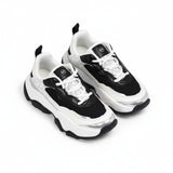 High-angle quarter view of a pair of kids' Michael Kors chunky platform trainers, displaying a multi-layered black, white, and silver mixed-media construction.