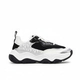 Side profile view of a kids' black and white Michael Kors sneaker showcasing a dramatic chunky wavy sole, black mesh base, and grey MK monogram panels with metallic silver accents.