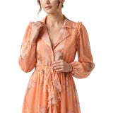 Studio shot of a model wearing the orange Milva Mi ruffled floral chiffon dress, showcasing its long blouson sleeves and open notched collar.
