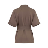 Back studio shot of the brown Milva Mi tailored blouse styled with the matching fabric waist belt, showcasing the clean, gathered silhouette at the lower hem.