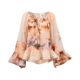 Front studio shot of the peach Milva Mi tropical print blouse shown unbelted, highlighting its relaxed silhouette, scoop neck, and flared ruffled sleeves.