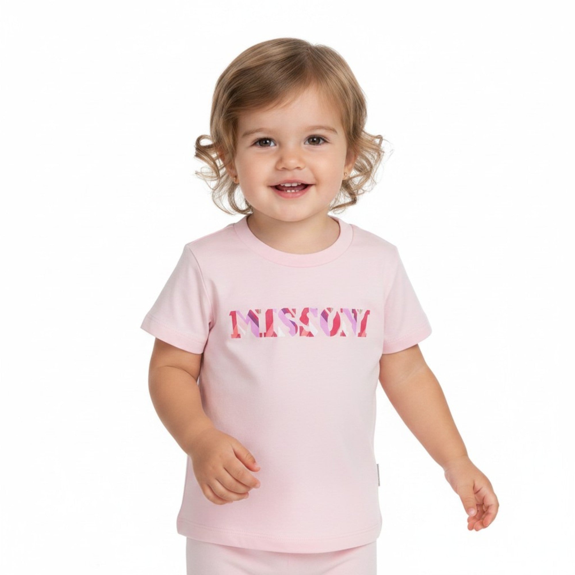 A smiling toddler baby girl modeling the Missoni light pink logo T-shirt paired with matching pink shorts against a seamless white studio background.