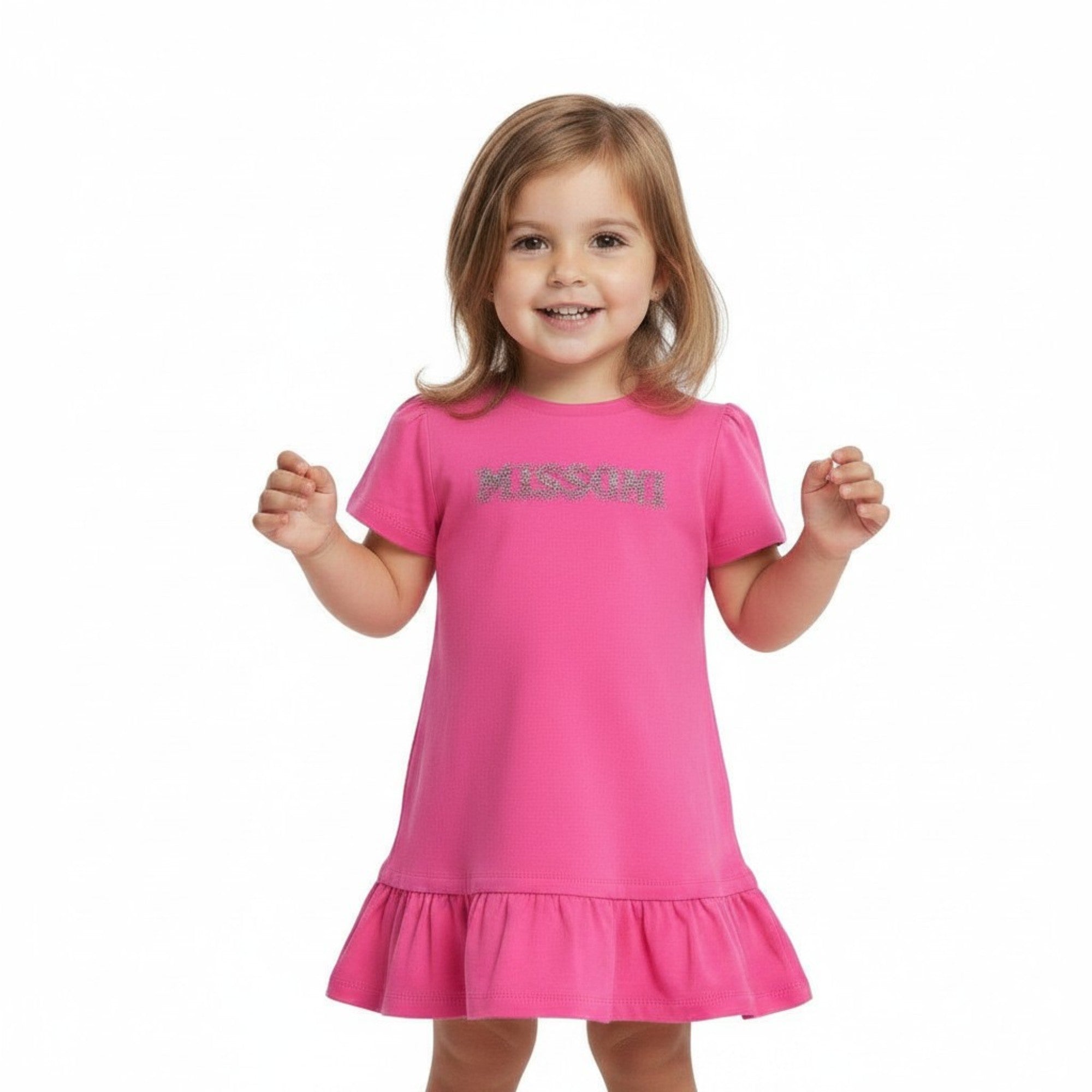 A young toddler girl standing and smiling happily, wearing a Missoni kids' fuchsia pink dress with puff sleeves and a ruffled hem against a white background.