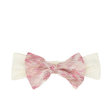 Front view of a Missoni Kids girls' headband featuring a large, decorative space-dyed bow with metallic pink lurex threads on a wide off-white stretch band.