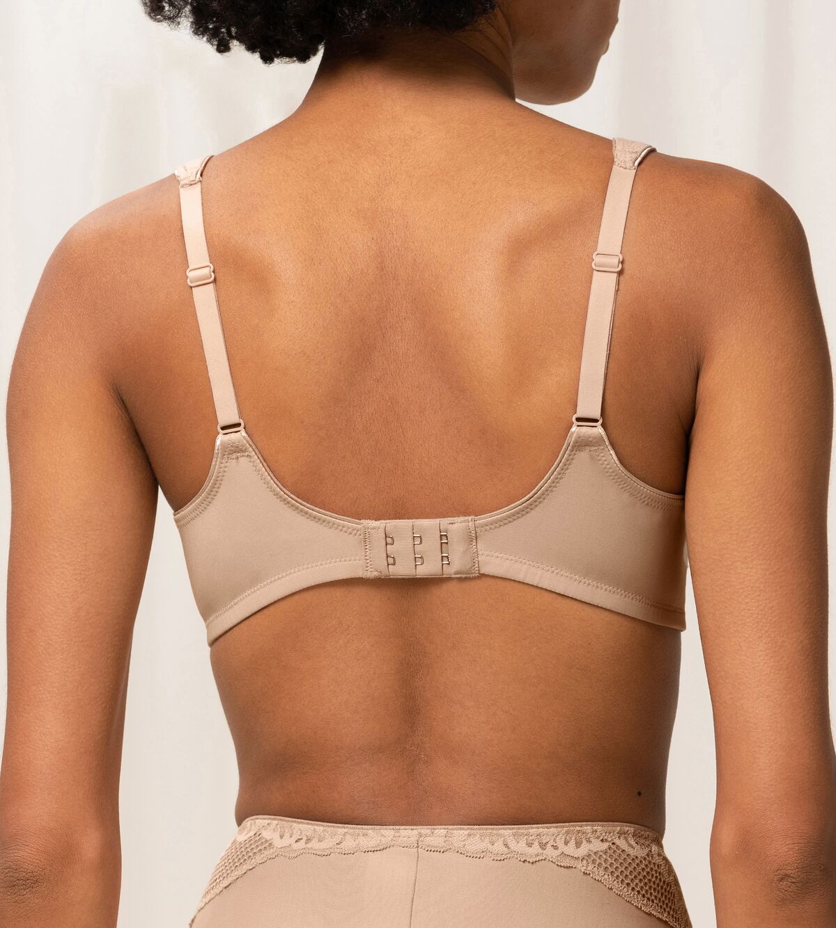 Model back view of the Triumph Modern Lace+Cotton beige non-wired bra, showcasing the adjustable straps, back closure and decorative floral lace. Shop the Latest Online