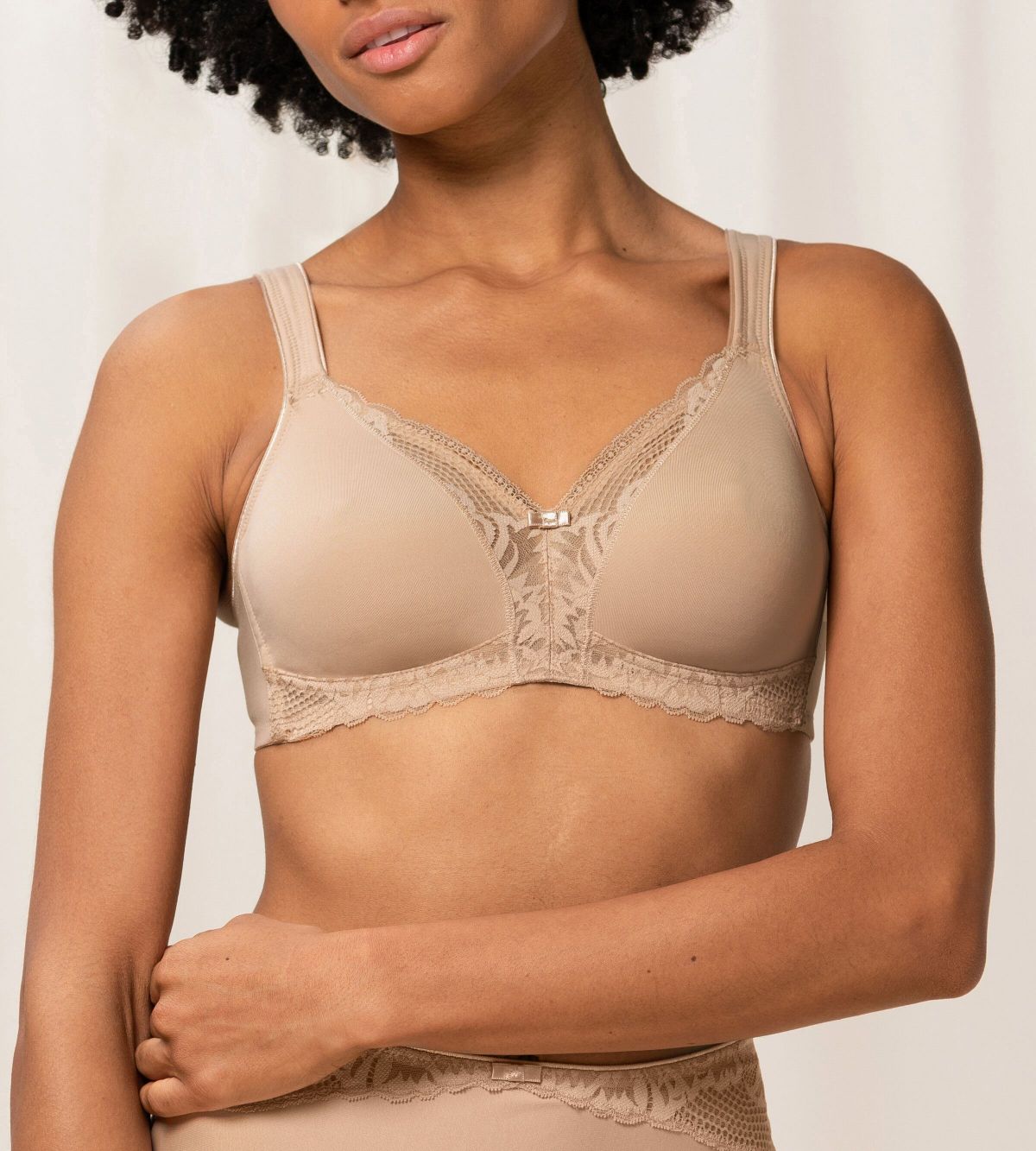 Model front view of the Triumph Modern Lace+Cotton beige non-wired bra, showcasing the cotton cups and decorative floral lace. Shop the Latest Online