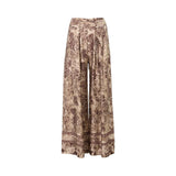Momoni high-waisted wide-leg trousers featuring a vintage-style floral print in burgundy and tan. The pants have front pleats and a decorative border print at the hem, displayed against a white background.