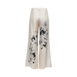 Back view of Momoni cream wide-leg trousers showing the continuation of the artistic black-and-white floral sketch print and tailored rear dart detailing.