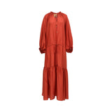Front view of a Momoni rust orange silk maxi dress on a mannequin, showcasing the ruffled tie neckline, drawstring waist, and tiered hem.