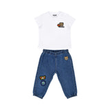 A baby's designer outfit featuring a white T-shirt with a star teddy patch and blue denim joggers with colorful graphics.