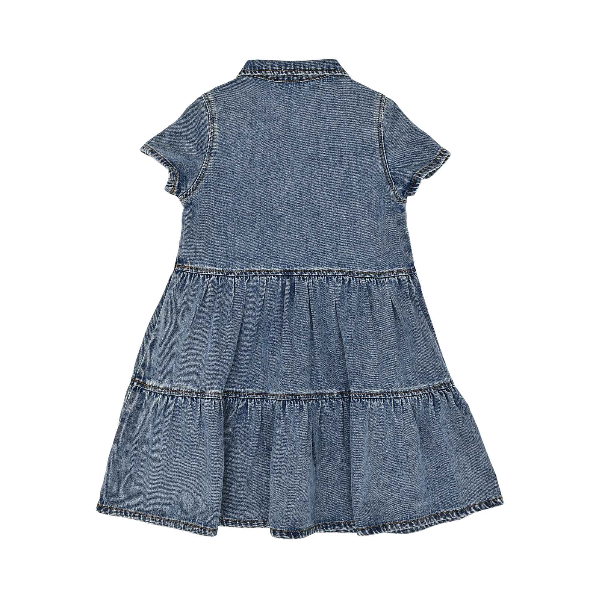 Rear view of the blue denim kids' dress showcasing the tiered skirt construction and simple yoke.