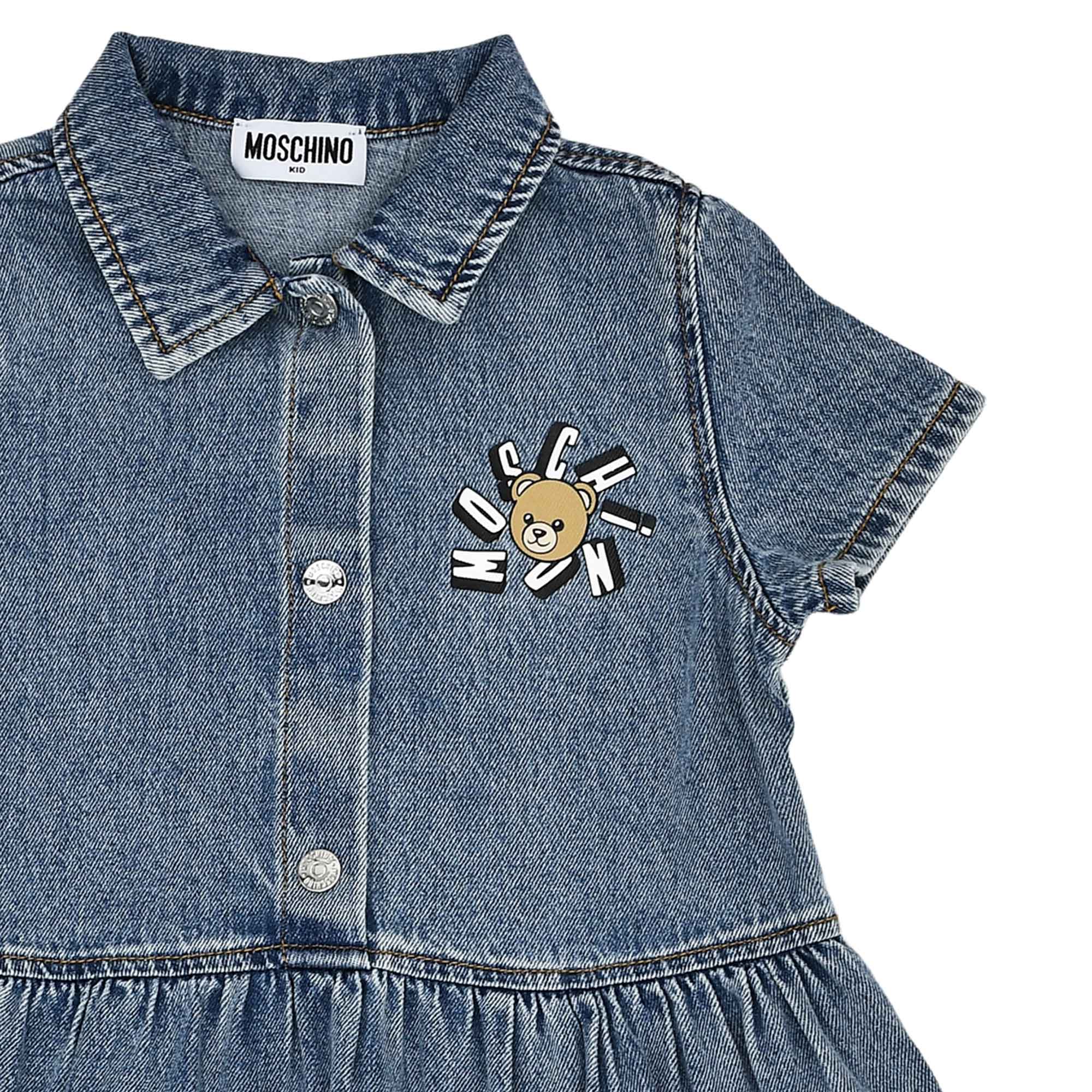 Close-up of the bodice highlighting the Moschino Kid neck label, silver-tone buttons, and the sunburst Teddy Bear logo embroidery.