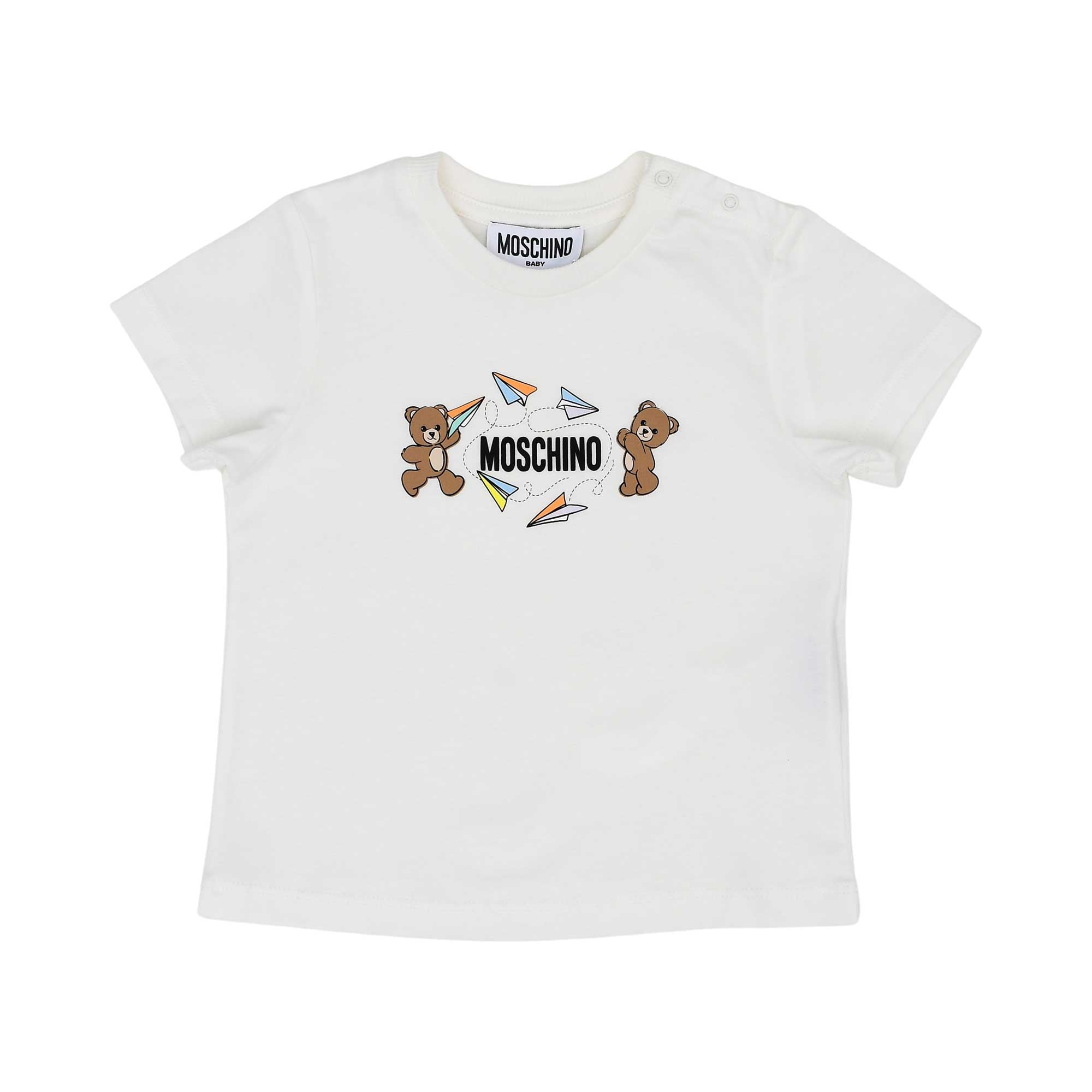 Detailed front view of the white Moschino Baby T-shirt highlighting the colorful paper plane and Teddy Bear logo with shoulder poppers.