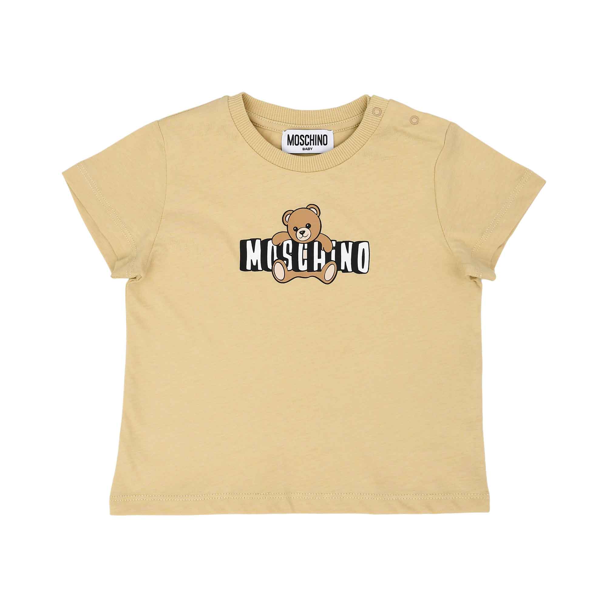 Detailed front view of the beige Moschino Baby T-shirt highlighting the iconic Teddy Bear graphic and brand logo with shoulder popper fasteners.