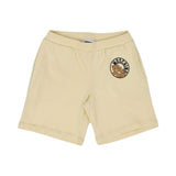 Front view of the buttercream yellow Moschino Baby shorts featuring an elasticated waistband and circular Teddy Bear patch on the left leg.