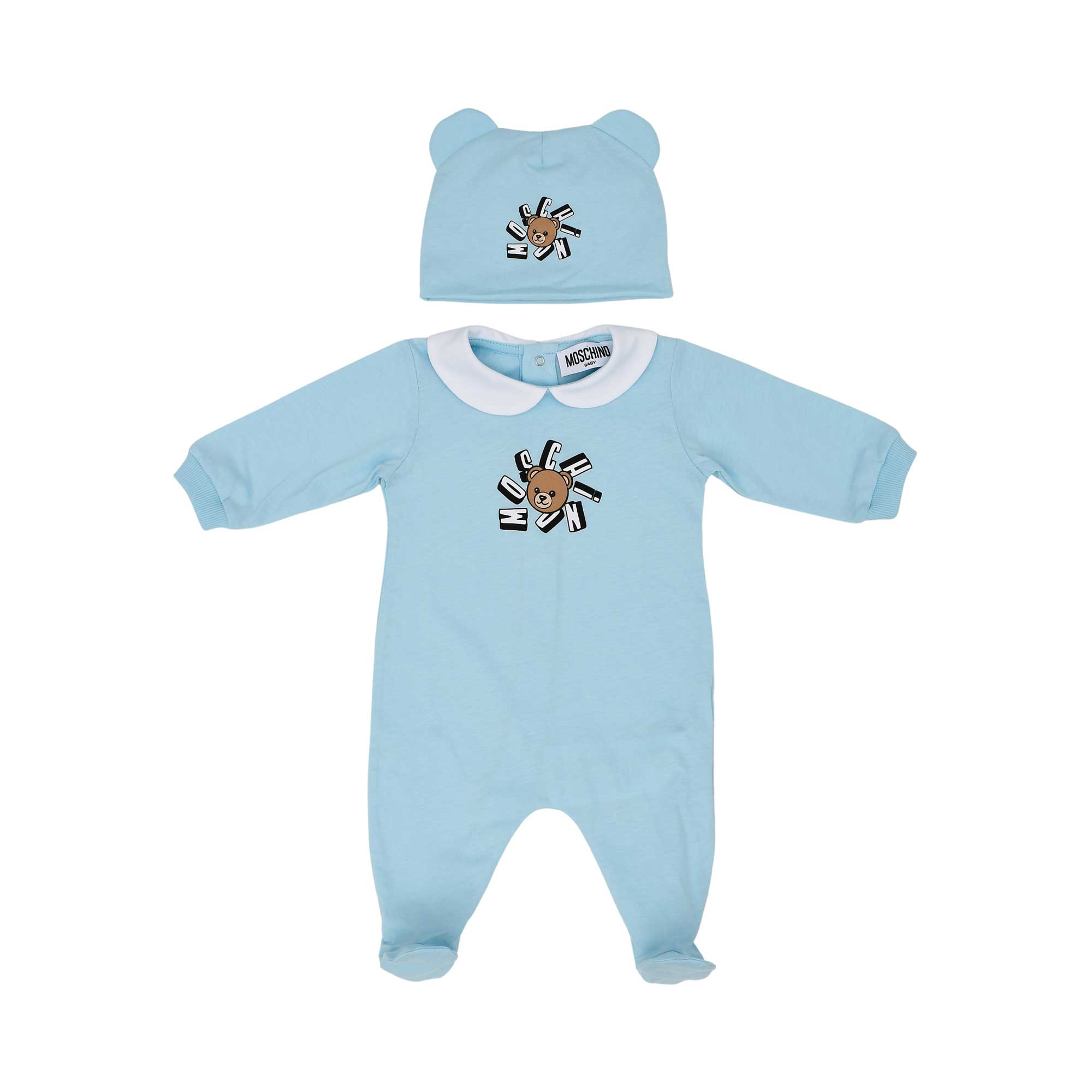 Front view of a blue Moschino Kids babygrow with a Peter Pan collar and a matching white hat with bear ears, both featuring the Teddy Bear logo