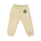 Front view of the cream joggers showing the Teddy Bear patch on the upper left leg and ribbed ankle cuffs.