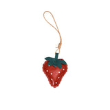 A handcrafted red leather strawberry charm by MUNI, featuring a green leaf top, white dot details, and a tan leather hanging cord against a white background.