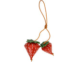 A handcrafted red leather strawberry charm by MUNI, featuring a green leaf top, white dot details, and a tan leather hanging cord against a white background.