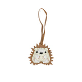 A handcrafted leather bag charm by MUNI shaped like a cute hedgehog with tan spikes, a cream-colored face, and small black eyes, featuring a long tan leather attachment loop.