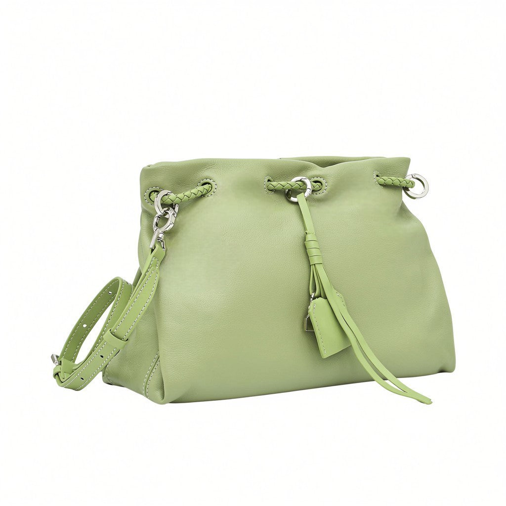 Close-up angled view of a light green leather MUNI drawstring shoulder bag with a hanging tag, available at BLUE SALON.