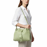 Woman wearing a white shirt and cream trousers carrying a light green MUNI drawstring shoulder bag from BLUE SALON.