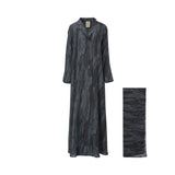 A full-length NERO abaya with a charcoal and blue abstract marble print, featuring a lapel collar and wide sleeves, shown alongside a matching folded scarf.