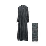 Back view of the NERO marble-print abaya showing the continuous floor-length pattern and a small gold brand emblem at the nape of the neck.