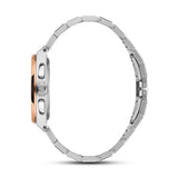 Side view of a silver-toned watch with a rose gold-toned bezel, two pushers, and a crown. It has a silver-toned metal link br