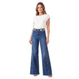 Full-length model view of a smiling woman with wavy blonde-highlighted hair wearing the high-waisted Nenette wide-leg jeans paired with a tucked-in white short-sleeve top.