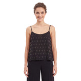 Front view of a smiling woman with an elegant updo hairstyle wearing the embellished black Nenette camisole top styled with matching black trousers.