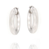 Pair of chunky, tubular silver-toned hoop earrings with a smooth, slightly matte finish and hinged post closures.