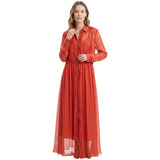 A woman modeling a long-sleeved, button-front maxi dress in a sheer rust-orange color, set against a plain white background.