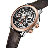 Silver-toned watch with rose gold-toned bezel, crown, and pushers. Black carbon fiber dial with silver-toned skeleton overlay