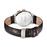 Back of a watch with a silver-toned stainless steel case, two rose gold-toned pushers, and a dark brown crocodile-embossed le