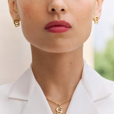 Lifestyle studio portrait of a model demonstrating the elegant drop, scale, and luxury shine of the Marina gold crystal earrings.