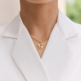 Lifestyle studio portrait of a model showcasing the fit, drape, and radiant shine of the Cerruti 1881 Marina gold crystal logo necklace.