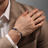 Lifestyle product photograph demonstrating the robust fit, scale, and navy color palette of the Sandro leather bracelet on a man's wrist.