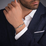 Lifestyle product photograph displaying the robust fit, scale, and mirror-shine metallic finish of the Carlo steel link bracelet on a man's wrist.