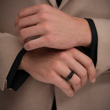 Lifestyle product photograph displaying the robust fit, scale, and monochromatic black finish of the Paolo ring on a man's hand.