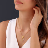 Lifestyle portrait photograph demonstrating the graceful drape, scale, and brilliant gold luster of the Camilla crystal pendant on a woman's neckline.