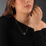 Lifestyle portrait photograph demonstrating the graceful drape, architectural scale, and brilliant gold shine of the Giulia pendant on a woman's neckline.