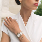 Lifestyle studio photograph showing a model wearing the Marina gold crystal bracelet alongside a green leather watch for a curated luxury look.