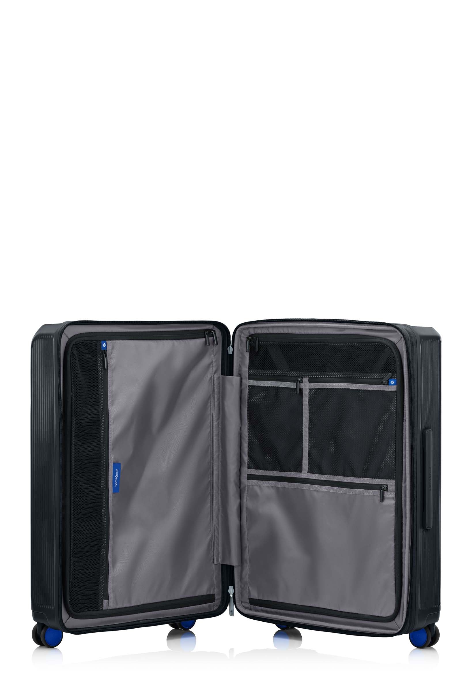 Open interior of the Samsonite Voypod Spinner medium in Black, revealing the grey recycled fabric lining, height-adjustable packing straps, and dual zippered divider pads. Find Online Today